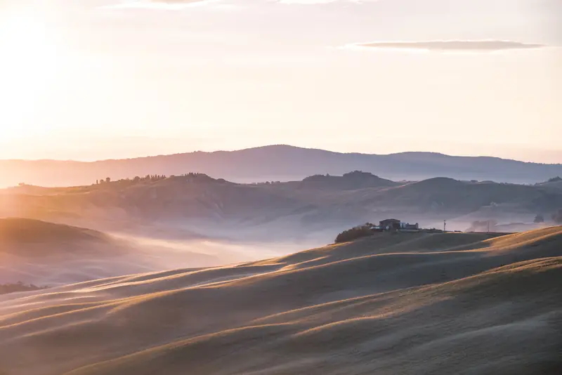 Alba sulle Crete dell'Orcia, colline ondulate avvolte dalla nebbia